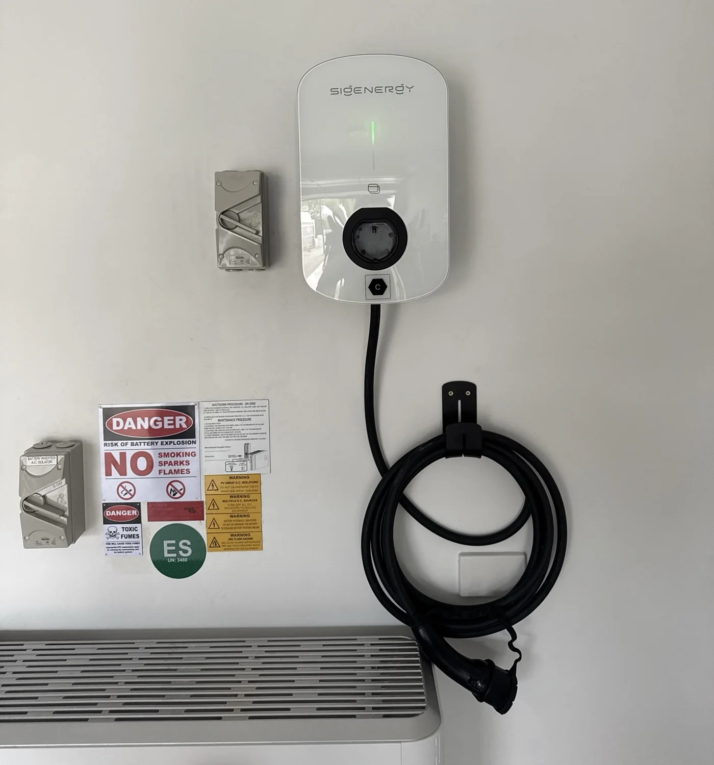 Sigenergy AC EV charger mounted beside existing home energy equipment with its cable holder
